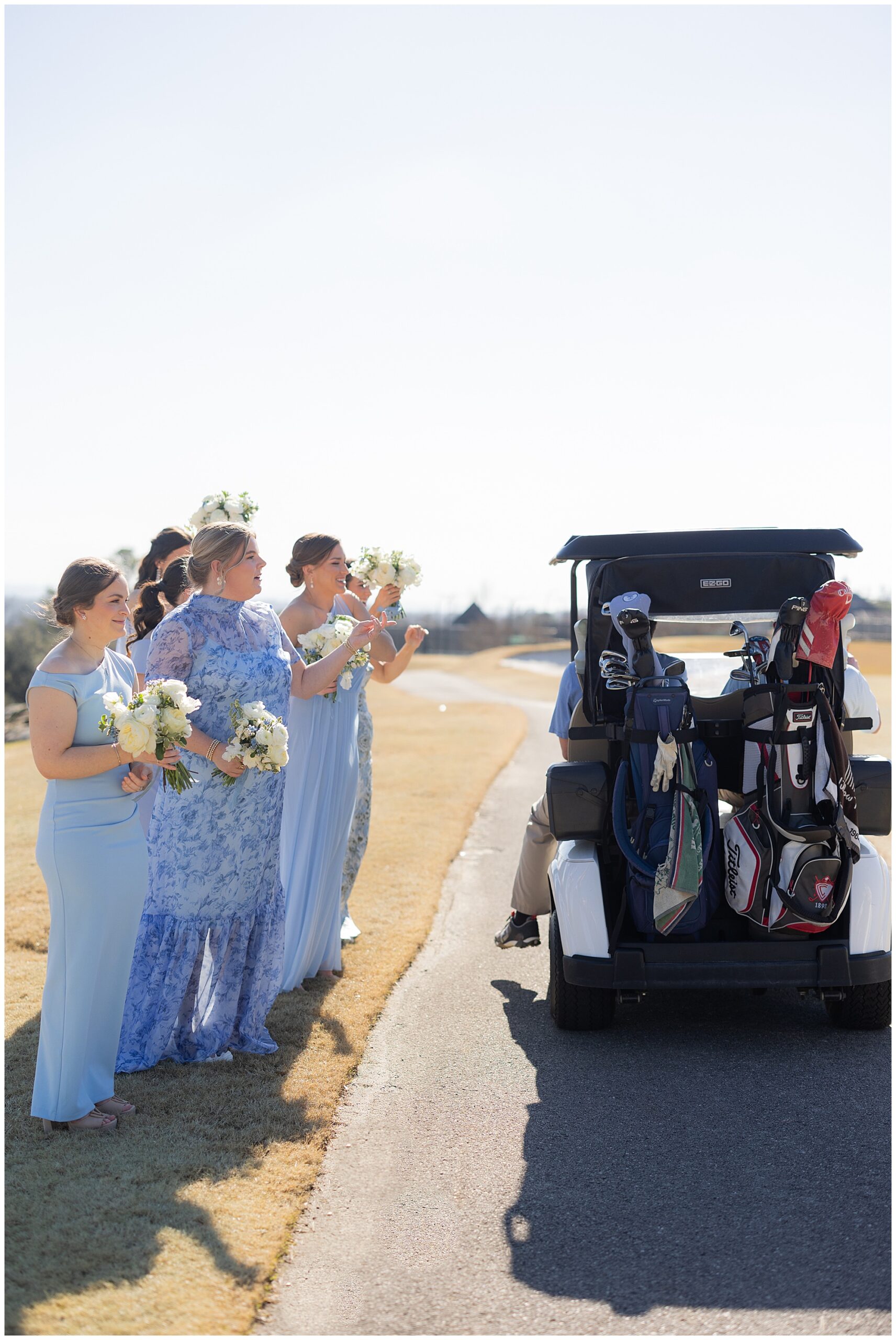 The bridesmaids stop to talk to a golfer as he drives by in his golf cart. 