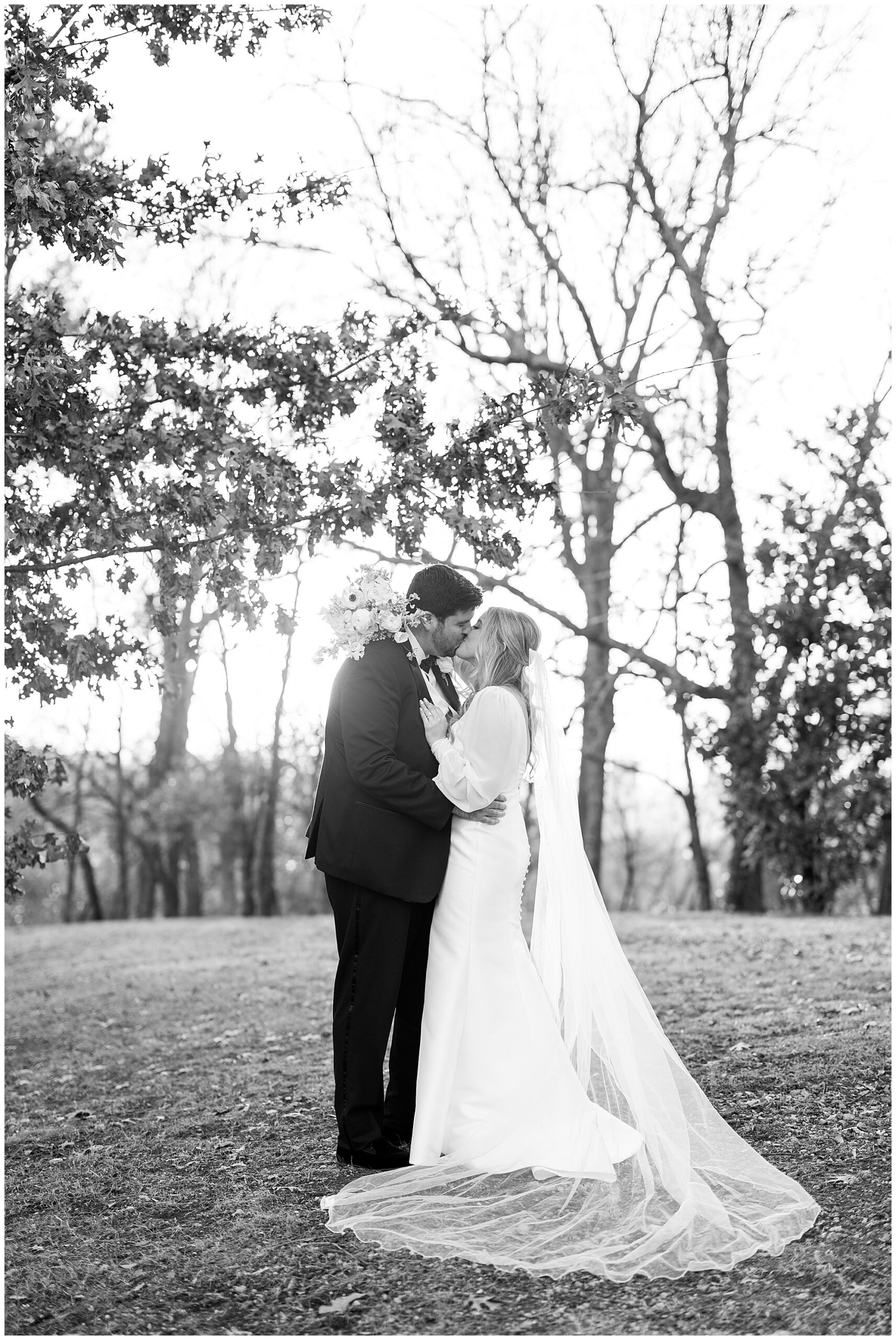 Faith and James kiss under an oak tree during sunset at Avondale Villa. 