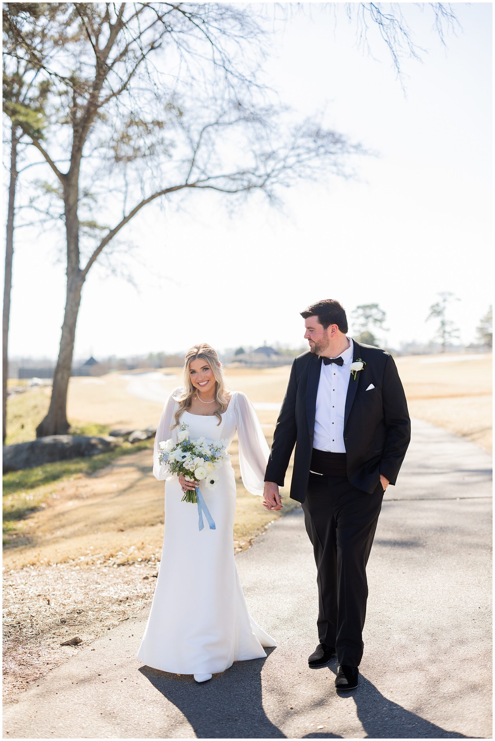 Faith and James walk along a gold cart path at the Vestavia Country Club. They are holding hands. 