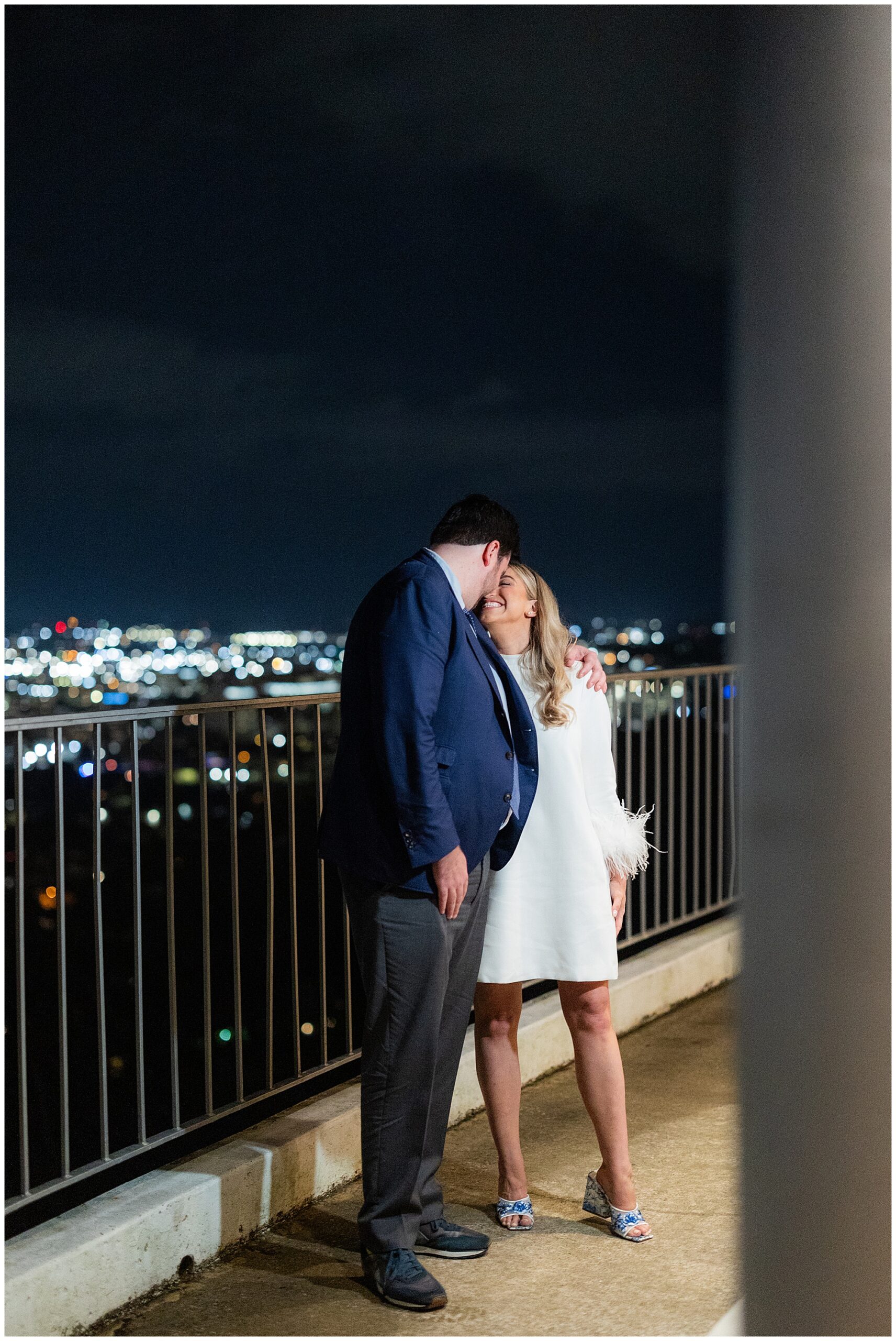 The bride and groom smile at each other as they stand on the terrace overlooking the city of Birmingham, AL. 