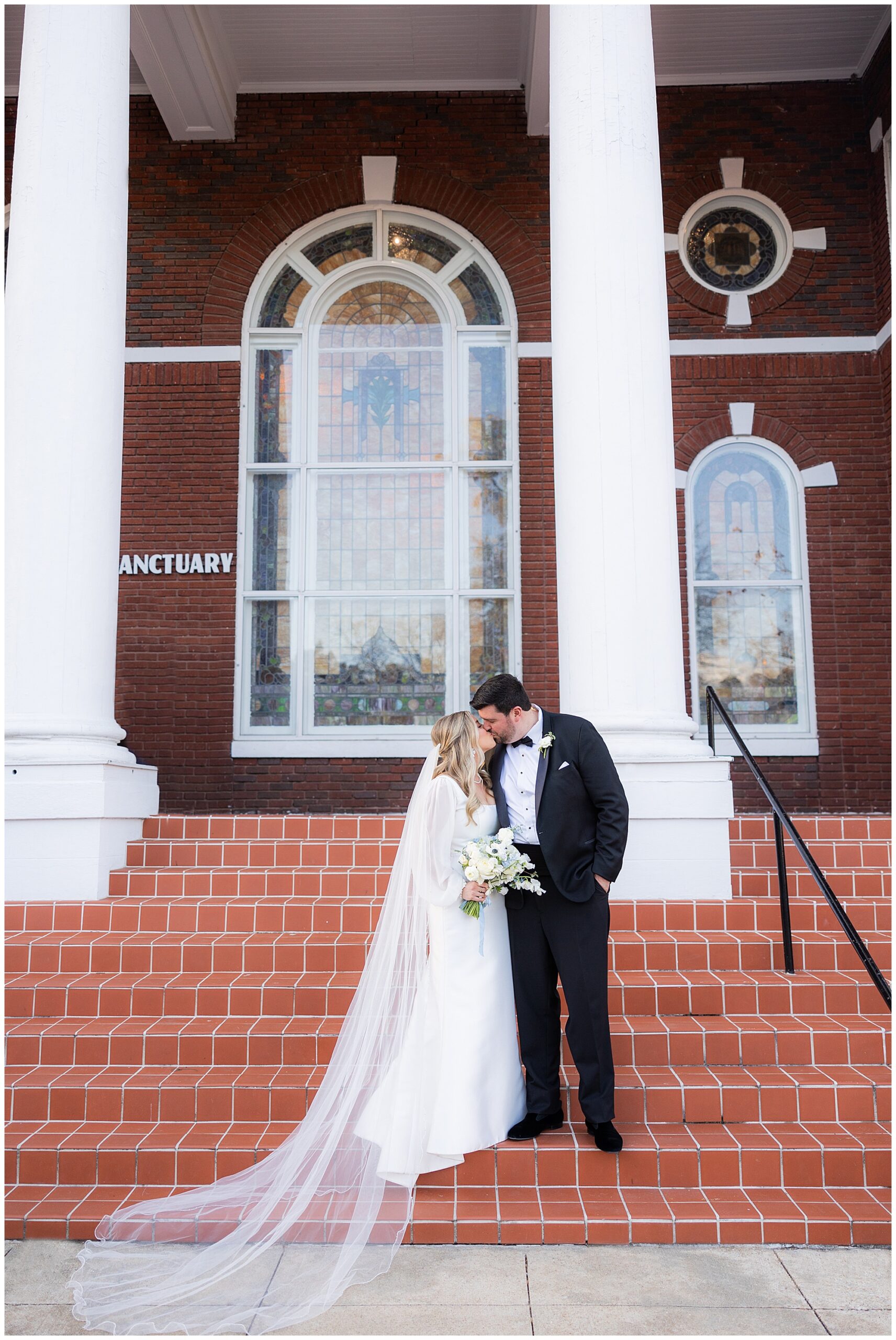 Faith and James stand on the front steps of Redeemer Community Church and share a kiss. 