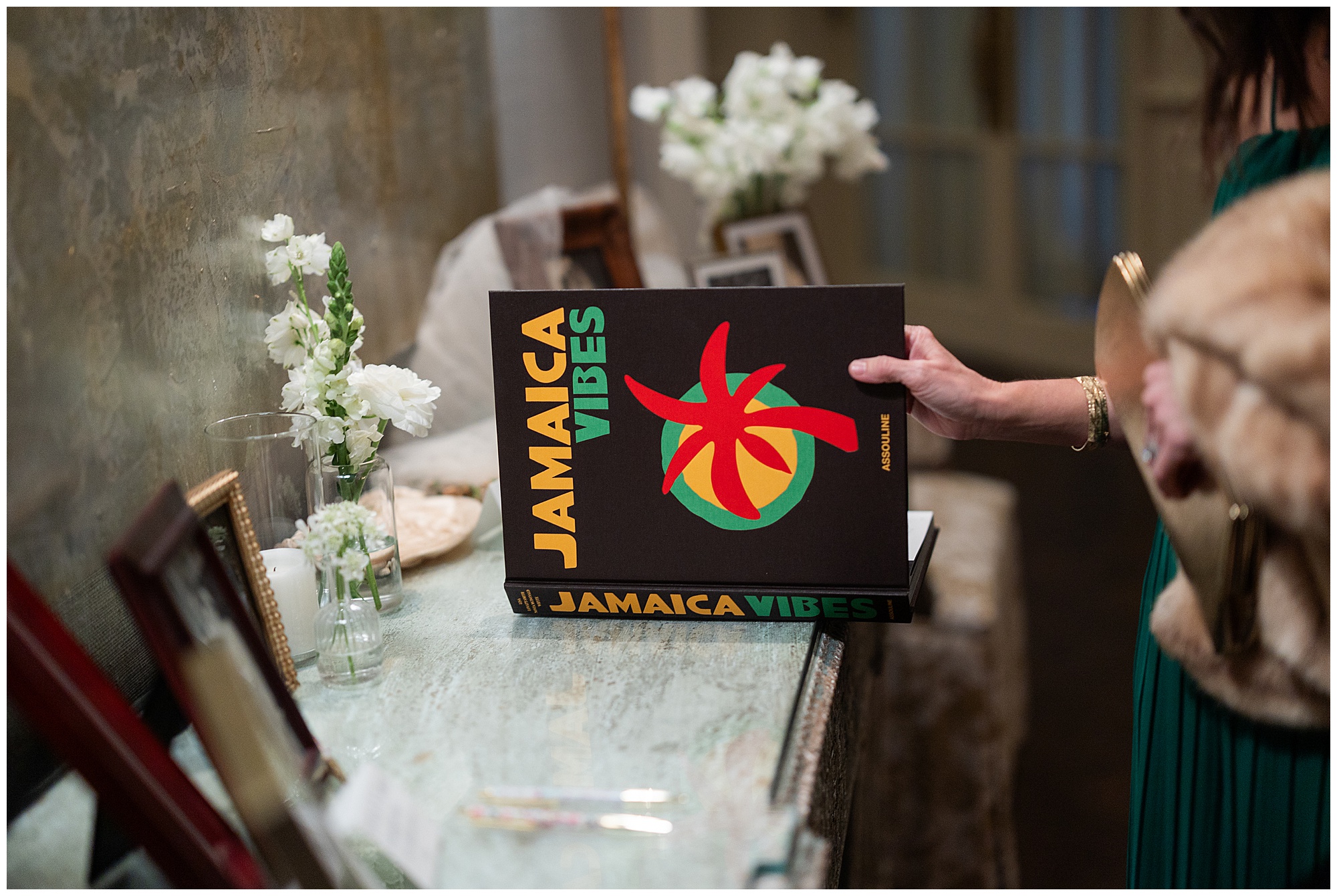 A guest opens the "Jamaica Vibes" coffee table book to sign. 