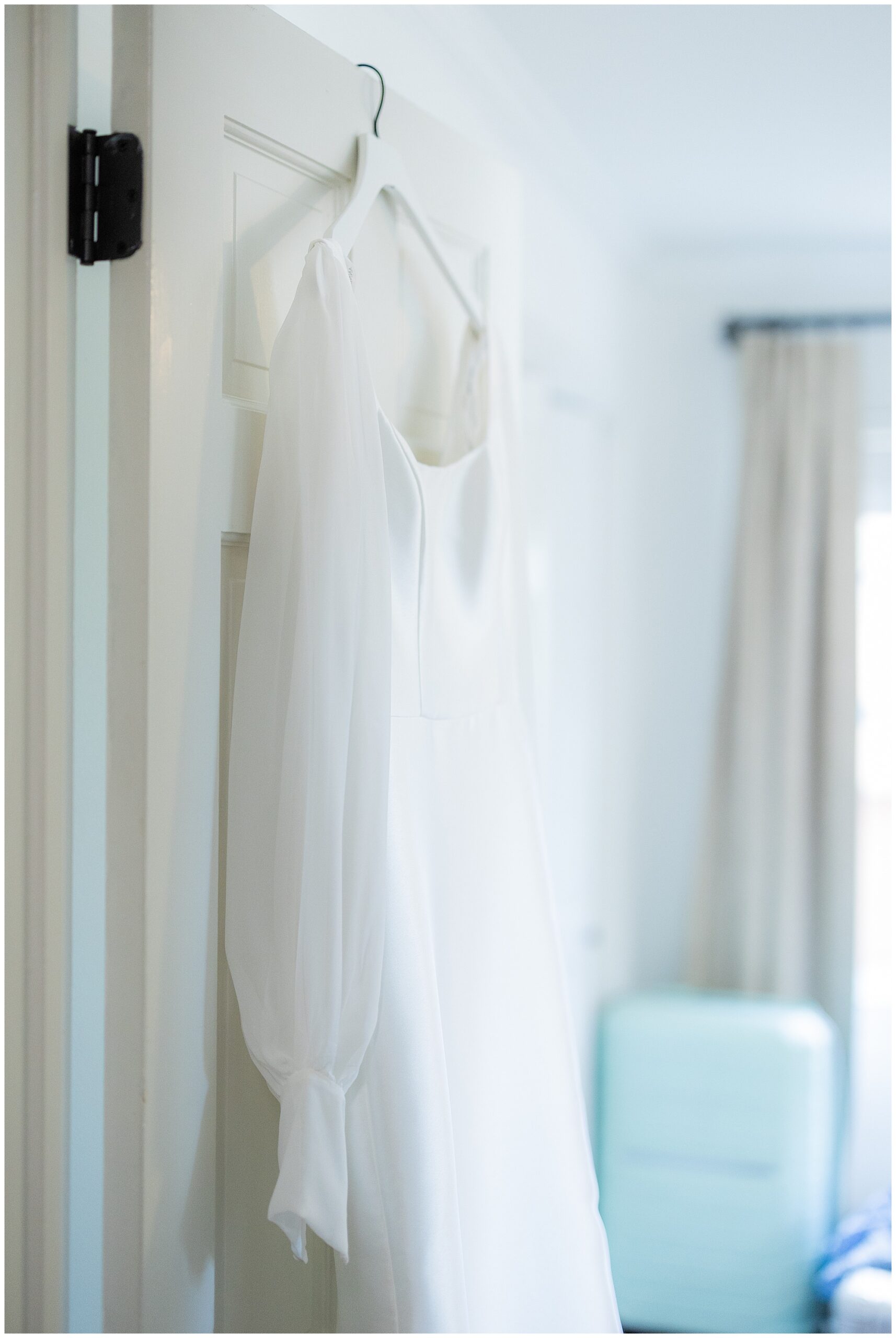 Faith's wedding gown hangs on an open door. 